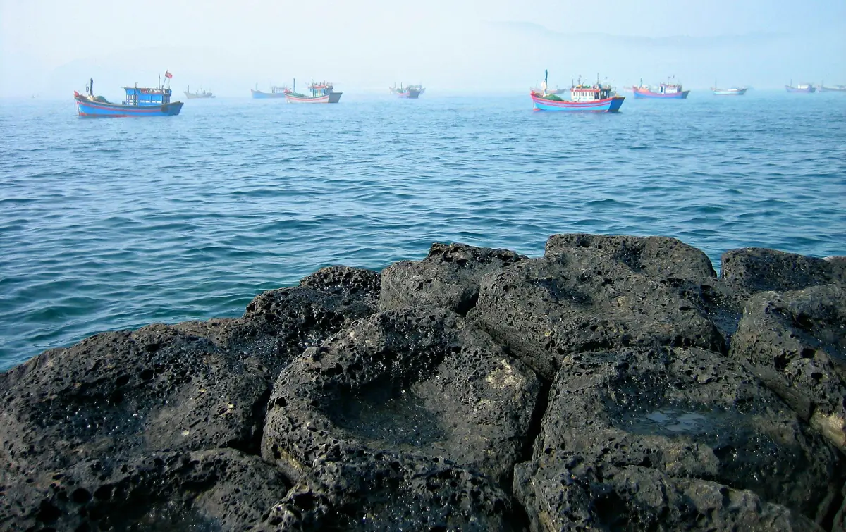 Basalt rocks with fishing boats anchored offshore